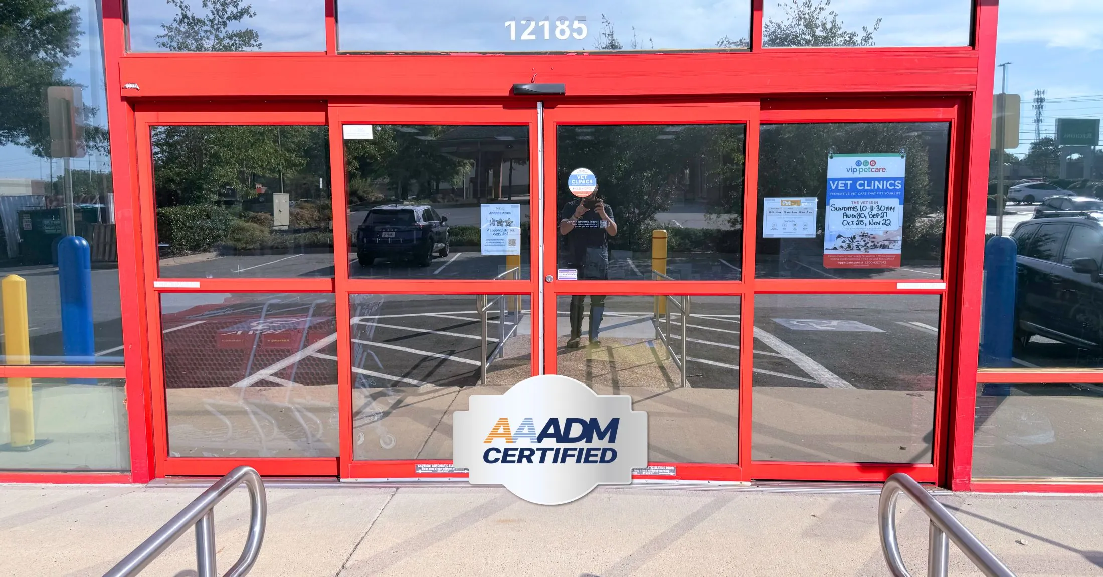 red automatic doors at a commercial storefront with an "AAADM Certified" seal overlay
